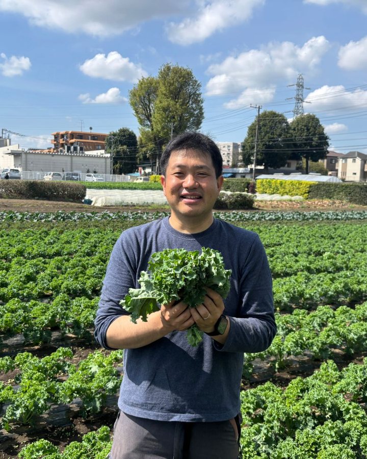 ケール畑でケールを持つ生産者 當麻大輝